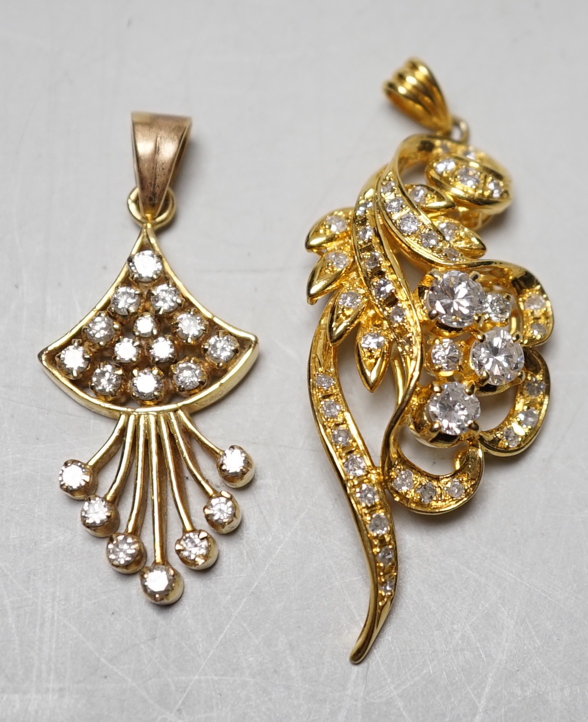 An Earl 18k yellow metal and diamond cluster ser scrolling pendant, overall 46mm and a yellow metal and diamond cluster set fan shaped pendant, gross weight 11.8 grams.